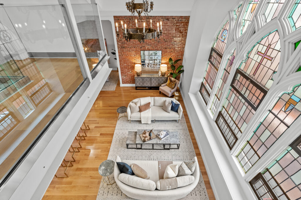 Stunning living room in the Sanctuary Condos, Capitol Hill, featuring historic stained glass windows, exposed brick, and luxurious modern decor.